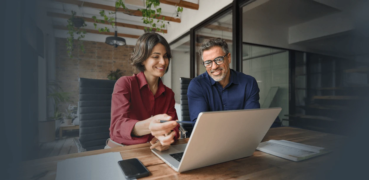 homem e mulher sorrindo enquanto olham para um notebook